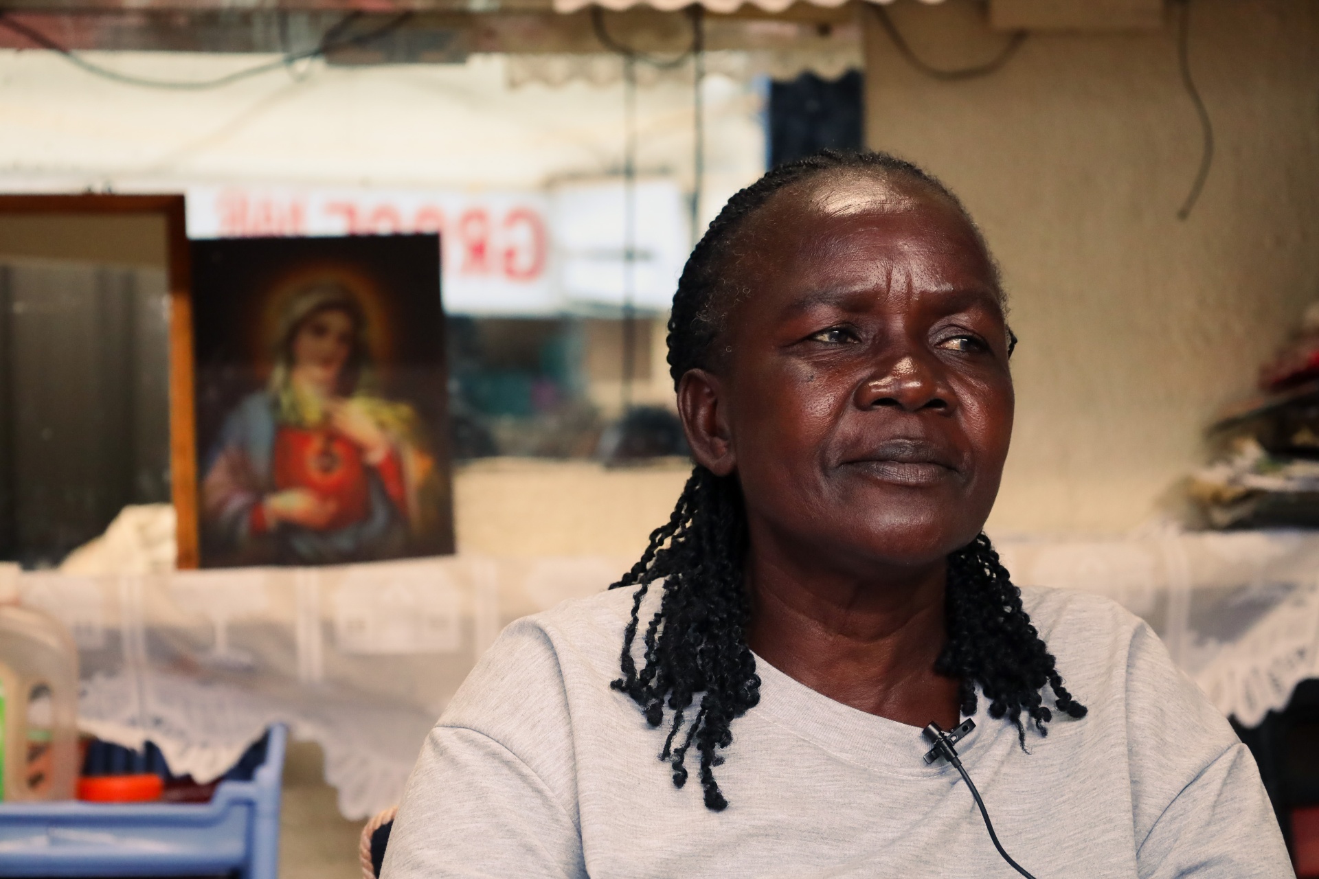 Braider seated inside her Kenyatta Market salon