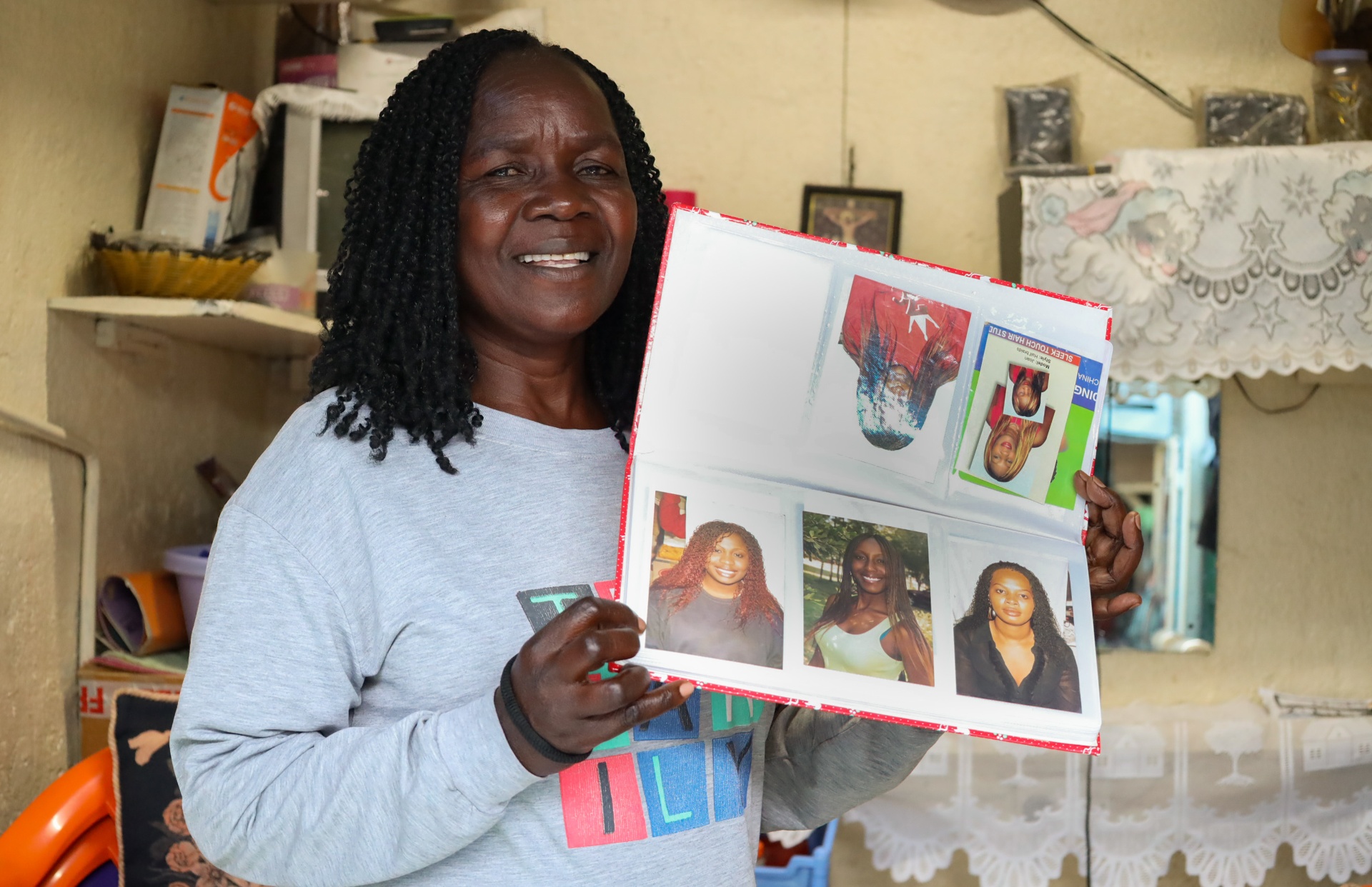 Braider smiling while holding a photo album of her work